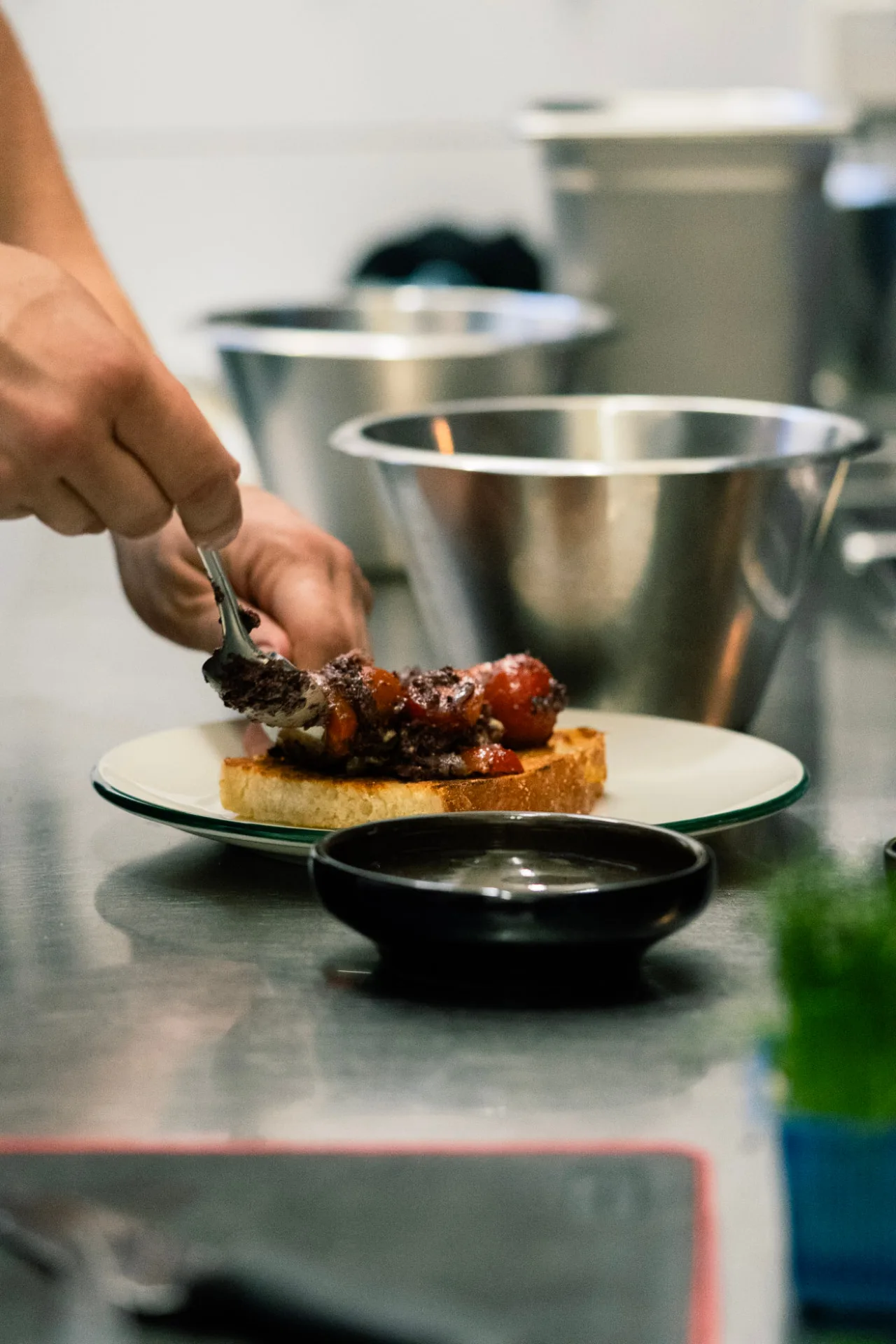 Kok hos CAVU anretter bruschetta med tomater og tapenade i køkkenet