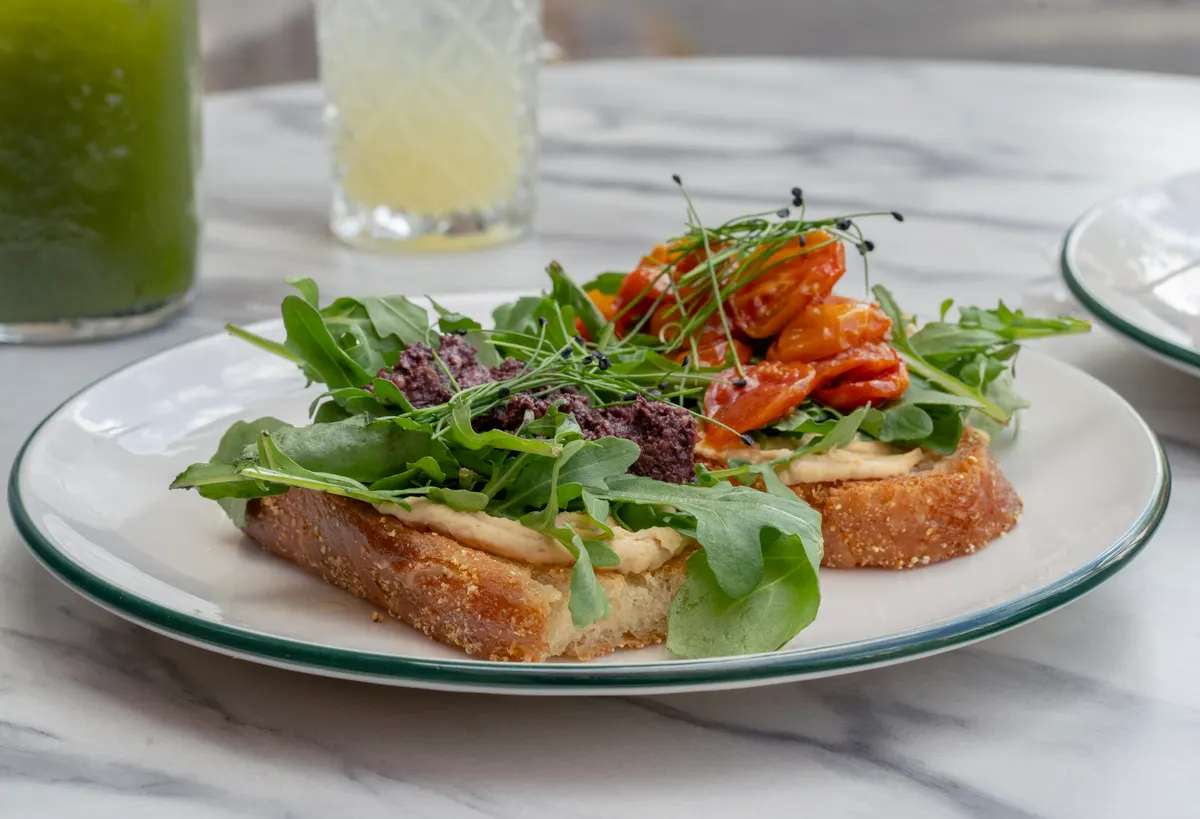 Brunchtoast med rucola og tomater ved siden af friskpresset juice